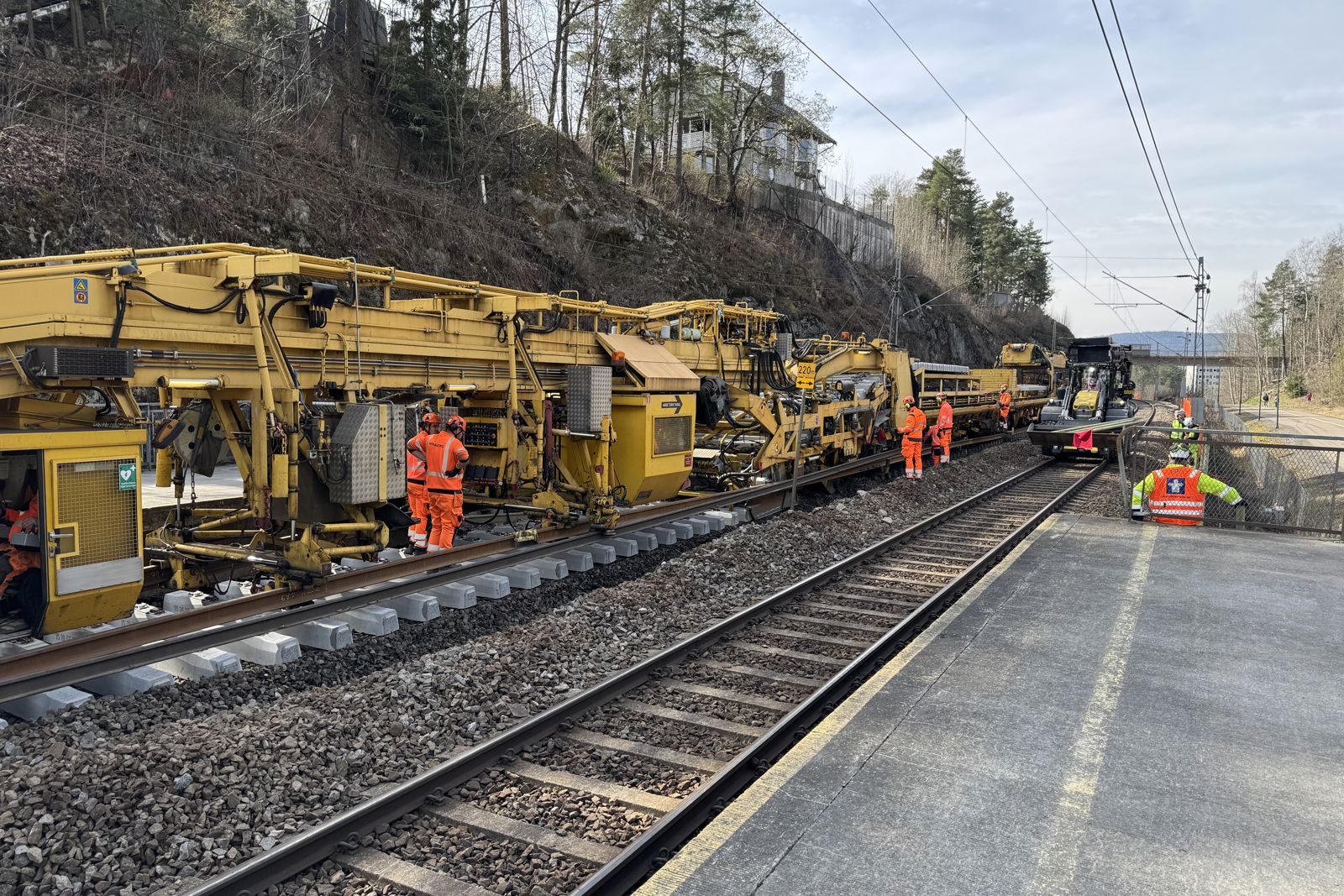 Stor gul maskin skifter skinner og sviller på jernbanen.