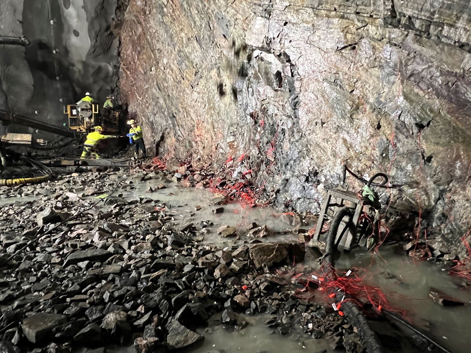 Foto av arbeidere som lader sprenghull med sprengstoff.