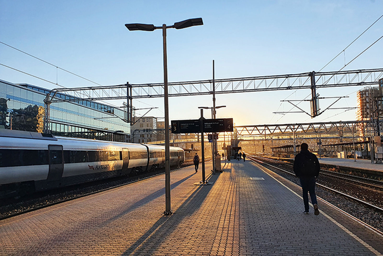 Bildet er tatt på en togplattform med tog på det ene sporet og høstlys.