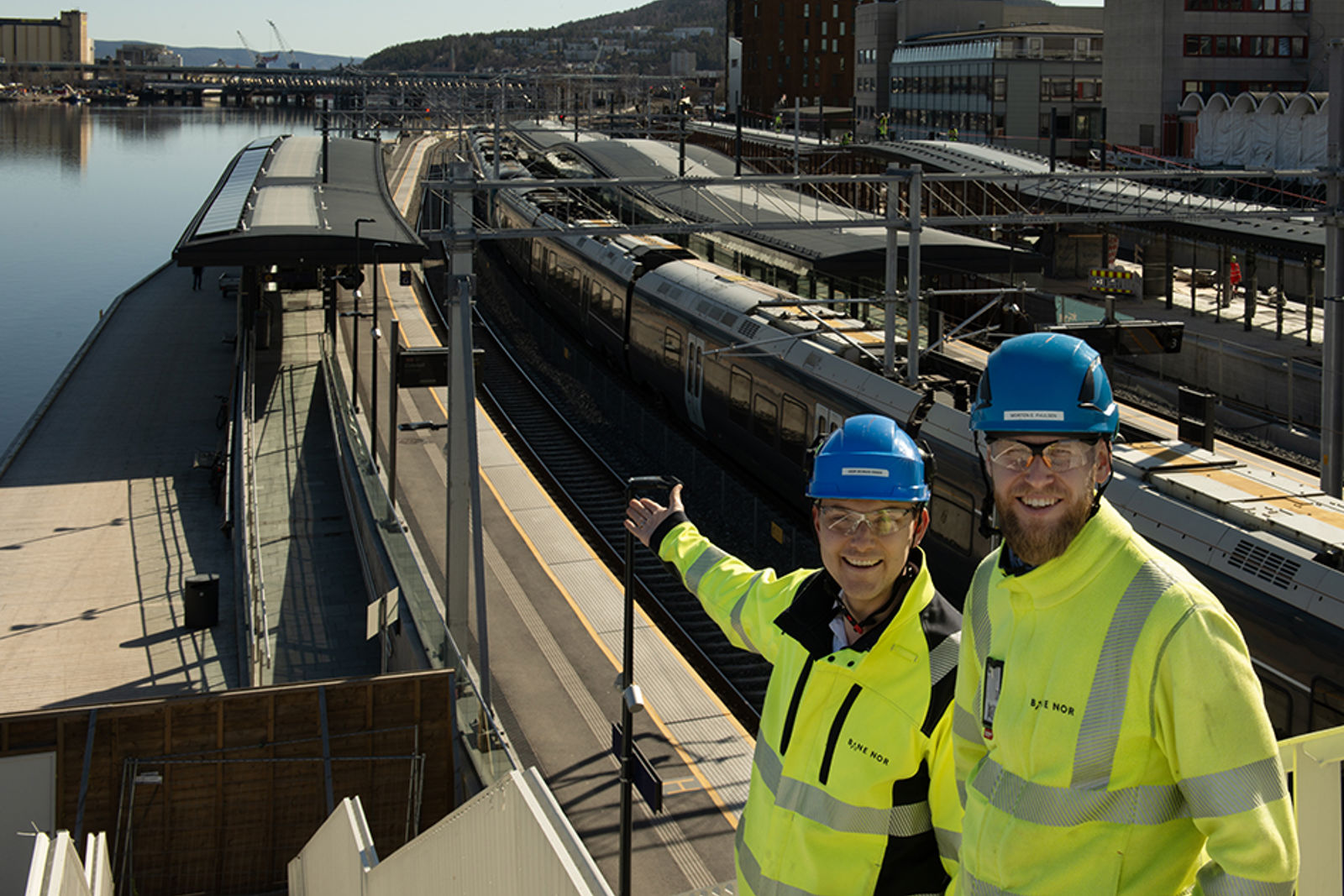 Bilde av to menn i vernetøy foran Drammen stasjon.