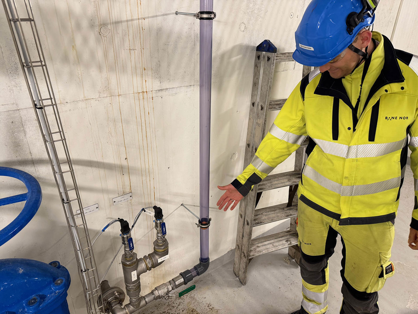 Mann i vernetøy peker på bordtennisball i gjennomsiktig rør.