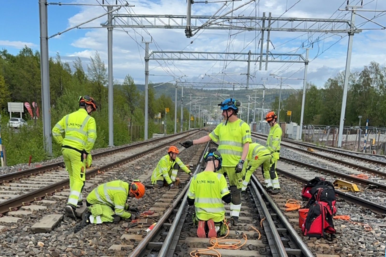 Menn i gule arbeidsklær vedlikeholder jernbanesporet.