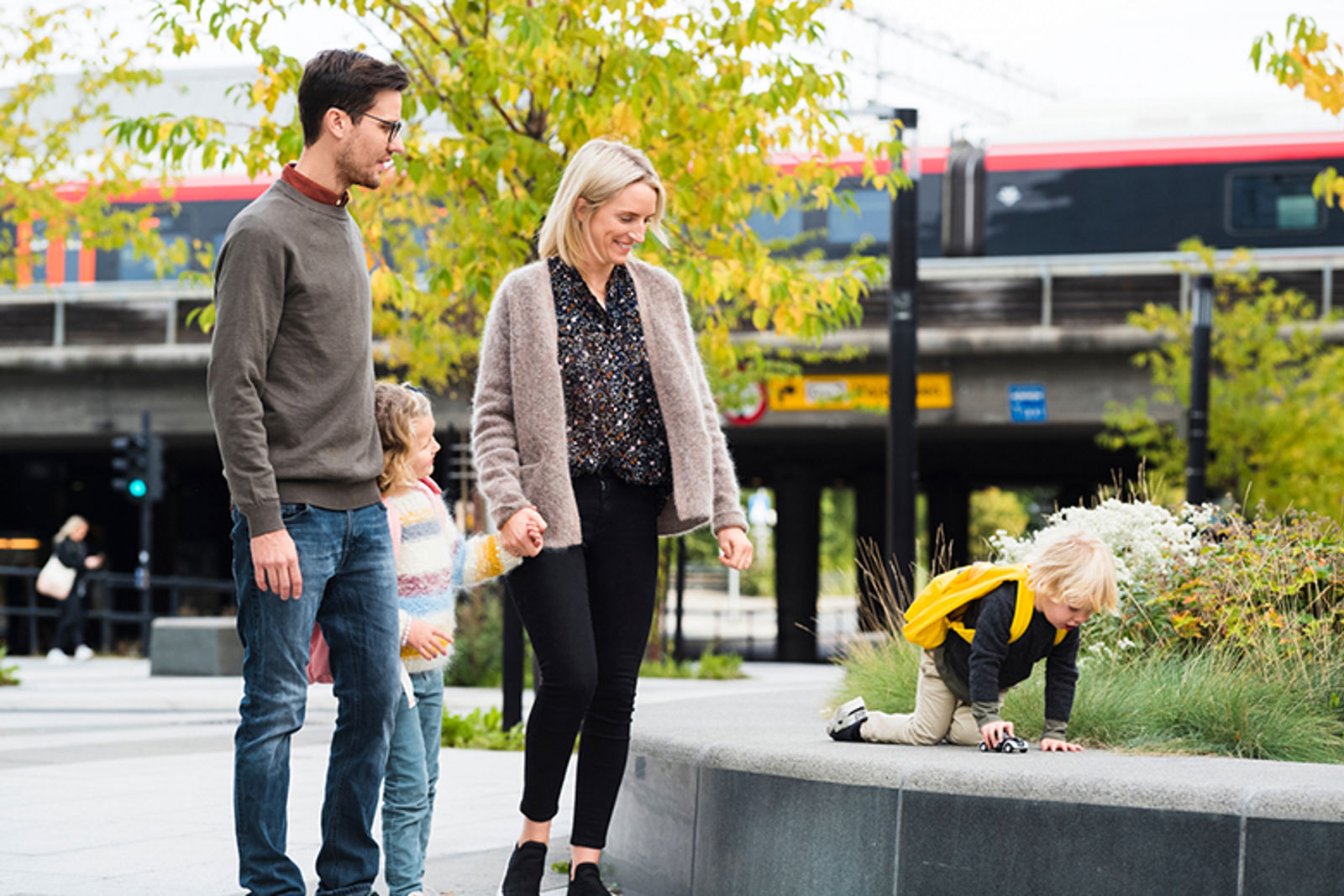 En far og mor rusler bortover et fortau sammen med to barn.