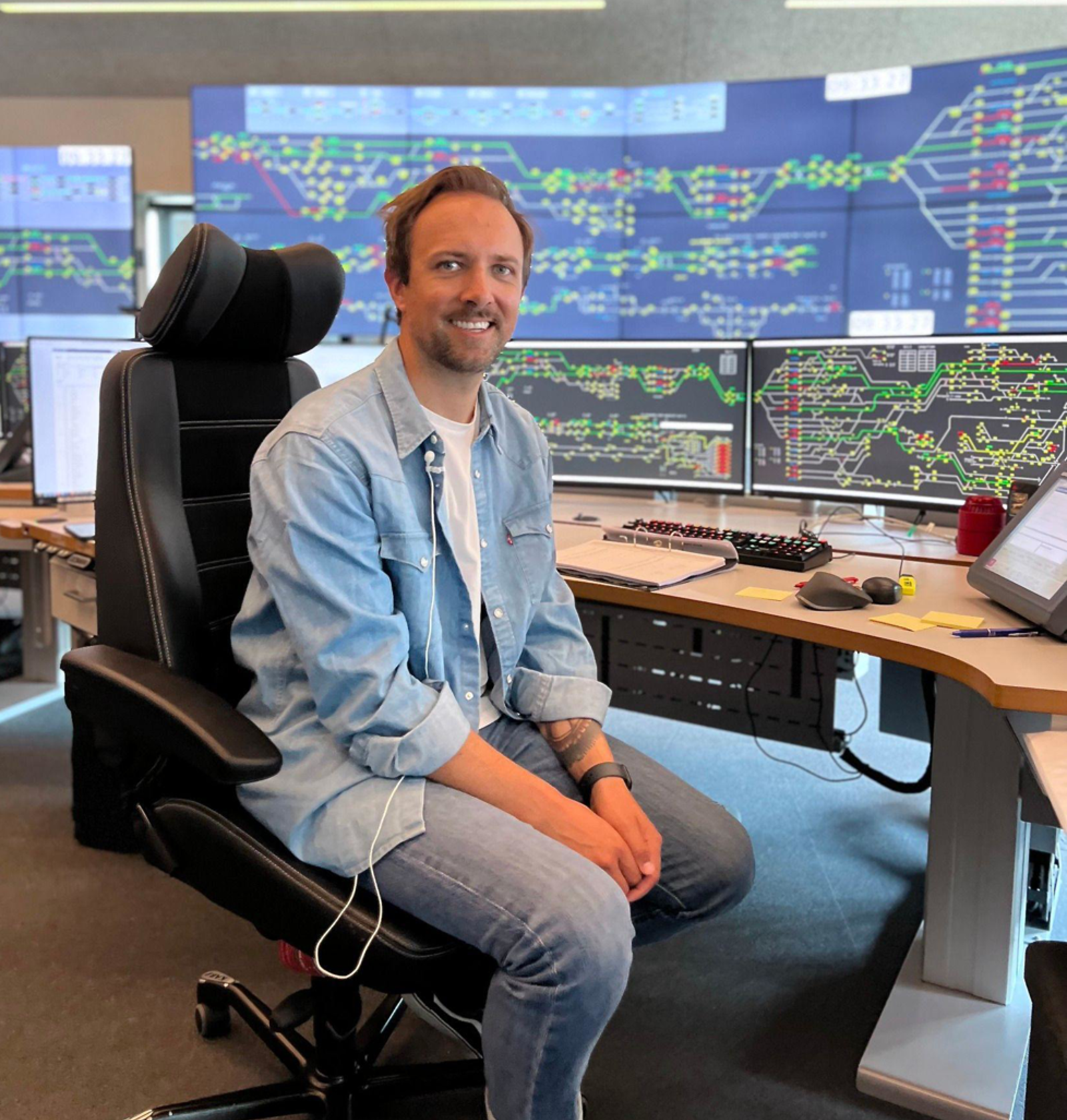 Sindre Lundemo sitter foran togleder skjermer