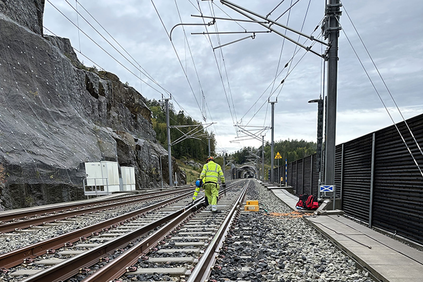 Mann i gult arbeidstøy går langs jernbanespor