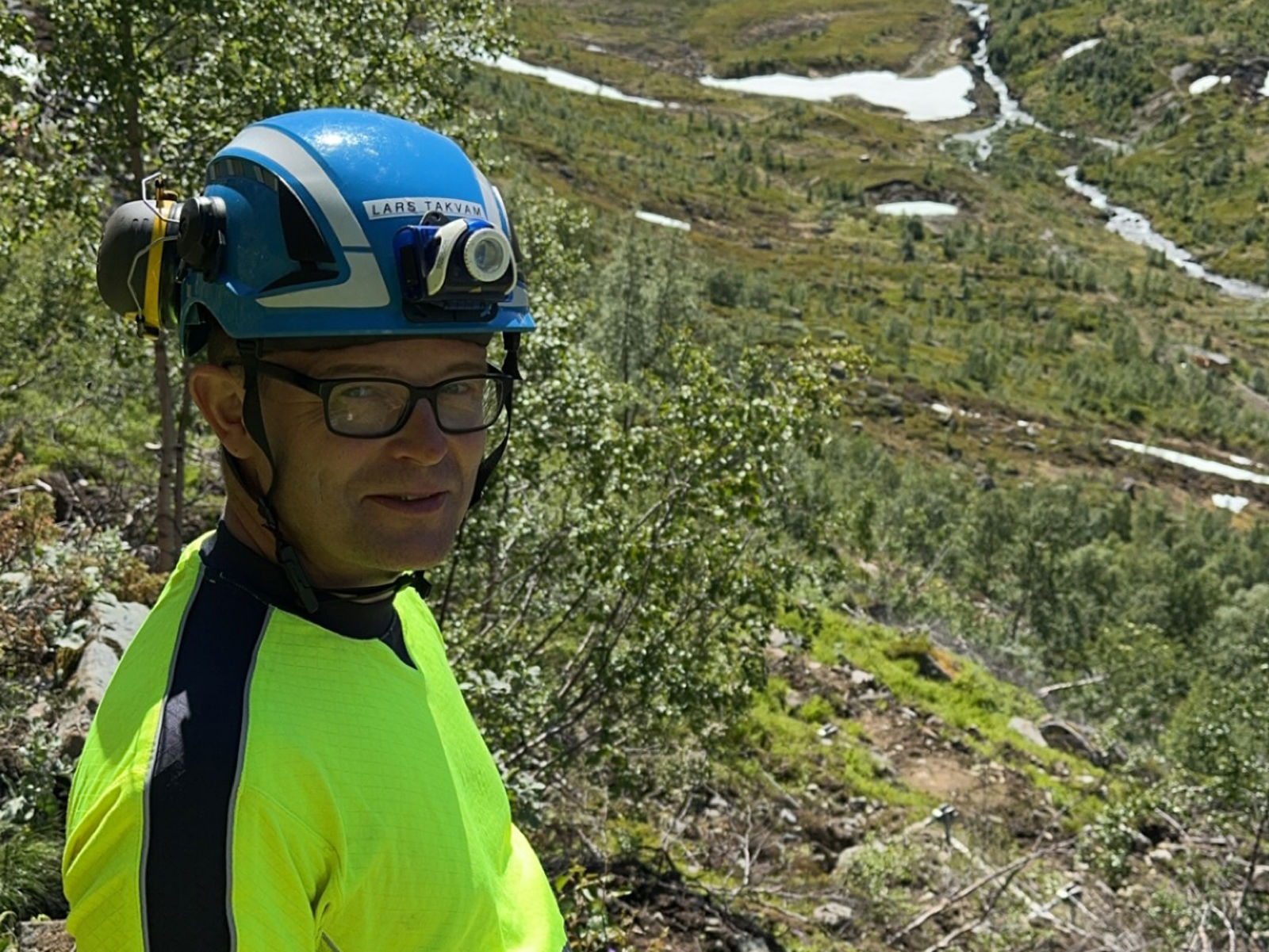 Mann med hjelm i fjellskråning